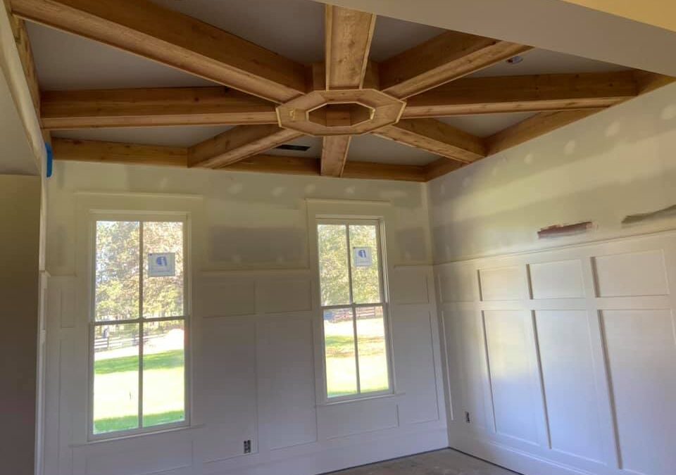 Photo of bedroom area of home under construction with wainscot walls and wagon wheel ceiling trays