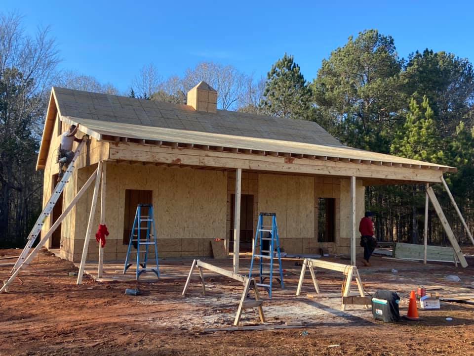 Custom outbuilding under construction with front porch-like carport area and workshop storage shed