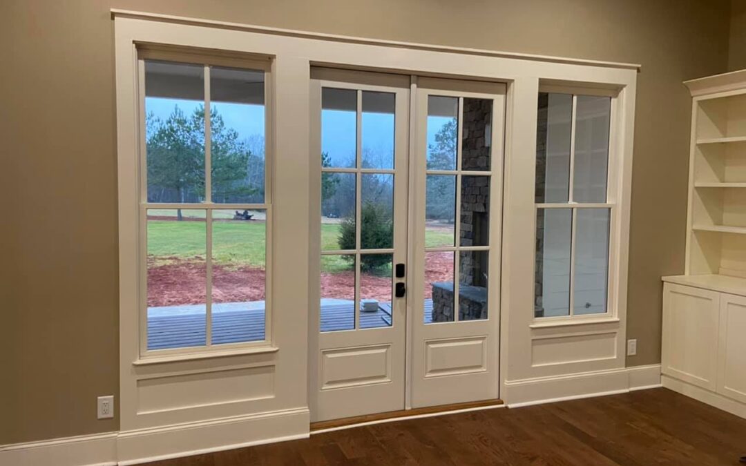 Photo of French doors and side panel windows leading to back patio and deck area