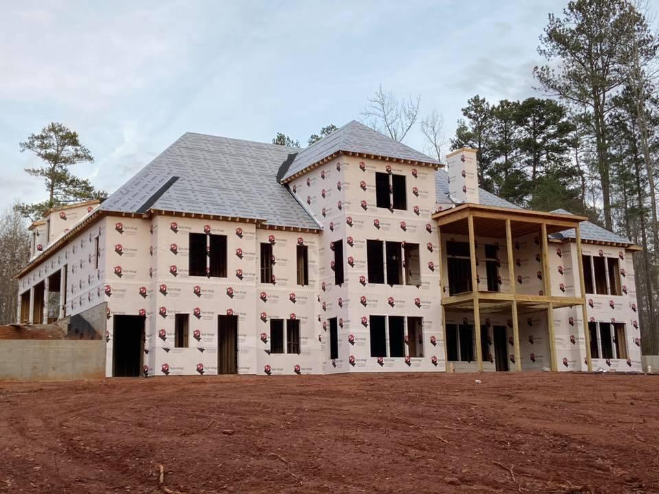 Three story home under construction. Photo of rear of home with double stacked decks and bump out on three floors