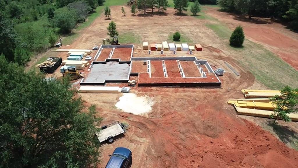 aerial view of home in early construction phase with stacks of delivered building materials