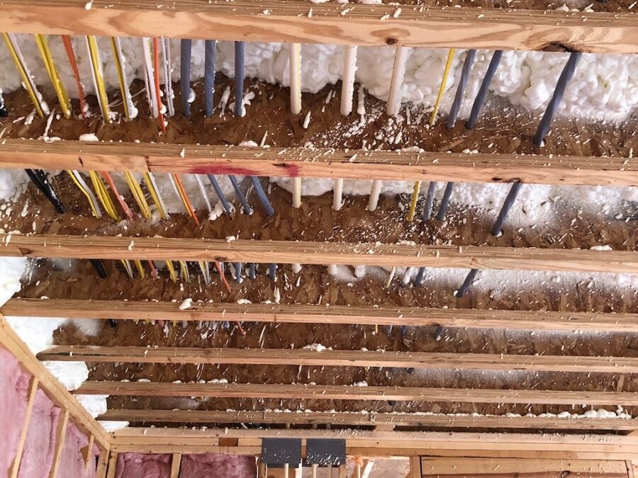 Photo of home under construction showing the wiring and and pipes running through the ceiling area with blown insulation